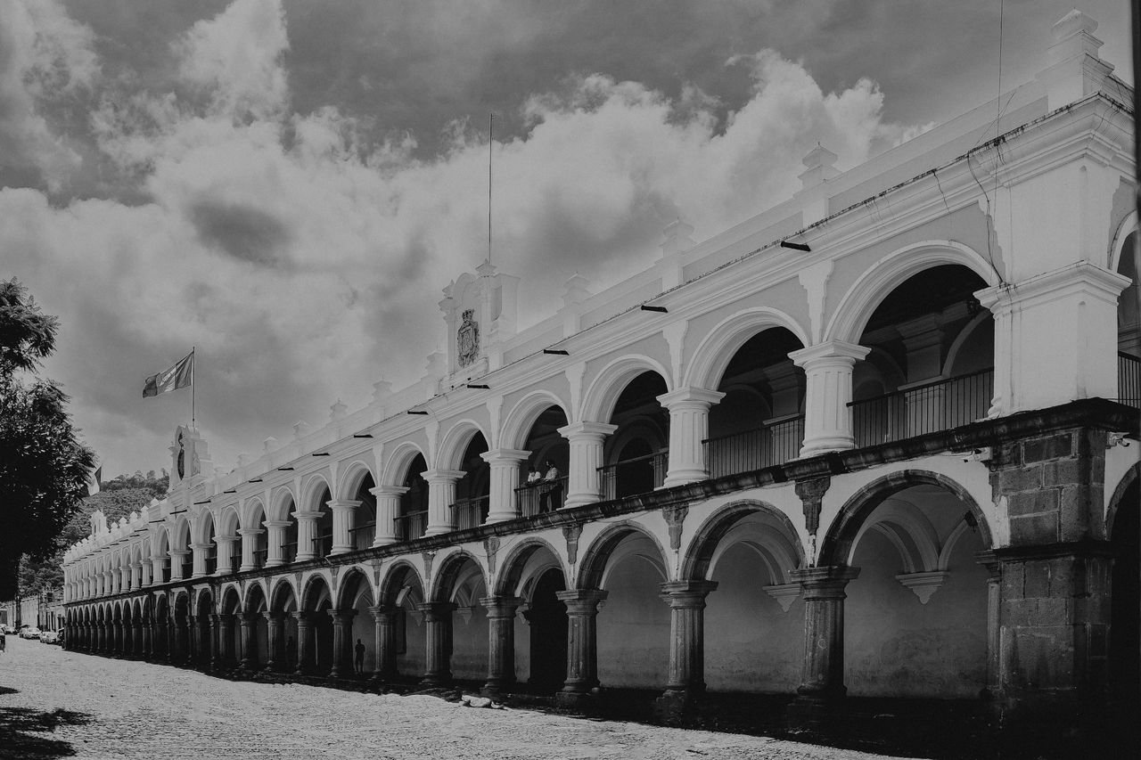 About Black and white photograph of the Palace of the Captains in Antigua Guatemala, showcasing its arches.